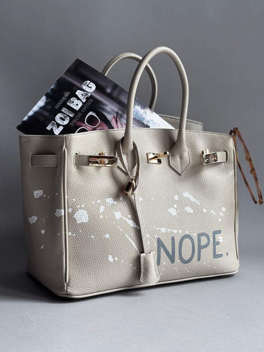 Béžová kožená kabelka Zoibag s ručně malovaným nápisem “Nope” a cákanci barvou.