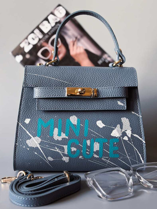 Designová modrá crossbody kabelka Zoi Bag z pravé italské kůže s ručně psaným nápisem a cákanci barvou.