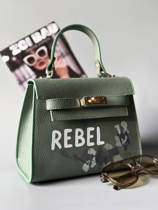 Designová pistáciová kabelka Zoi Bag z pravé italské kůže s ručně psaným nápisem "Rebel" a cákanci barvou.