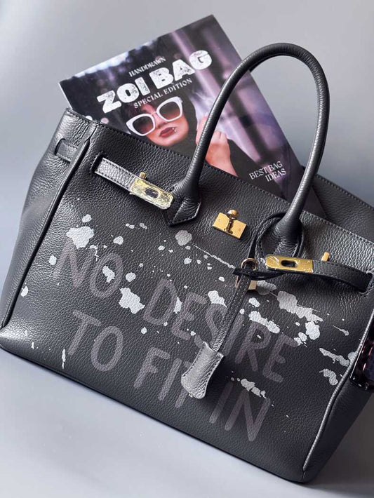 Luxusní designová kabelka vyrobená z kvalitní italské kůže s ručně psaným nápisem a cákanci barvou. Ikonické zapínání na zámek s klíčkem.