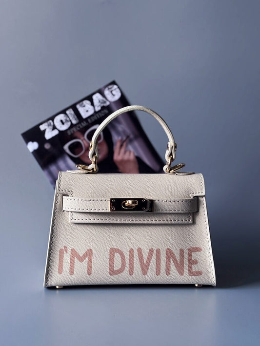 Designová luxusní světle béžová kabelka s ručně psaným nápisem, elegantním otočným zámkem a odnímatelným crossbody popruhem.