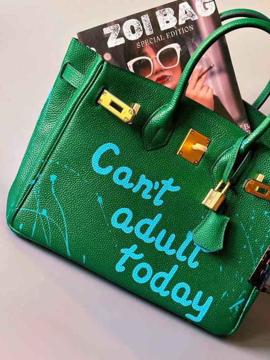 Designová zelená kožená kabelka Zoi Bag s ručně psaným nápisem a s cákanci barvou, se zámkem a klíčkem.