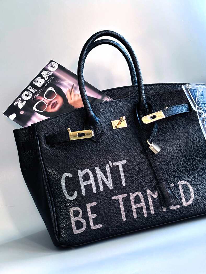 Černá kožená kabelka s ručně psaným nápisem "Can't be tamed"