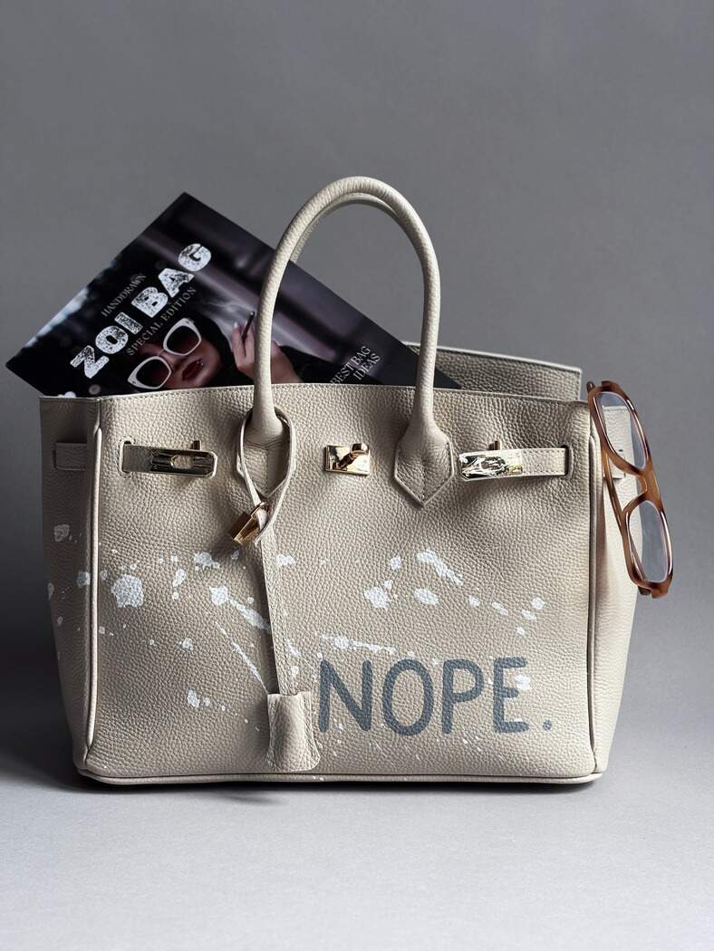 Béžová kožená kabelka Zoibag s ručně malovaným nápisem “Nope” a cákanci barvou.