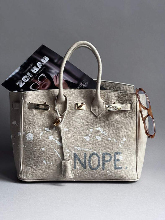 Béžová kožená kabelka Zoibag s ručně malovaným nápisem “Nope” a cákanci barvou.