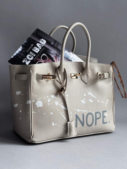Béžová kožená kabelka Zoibag s ručně malovaným nápisem “Nope” a cákanci barvou. 
