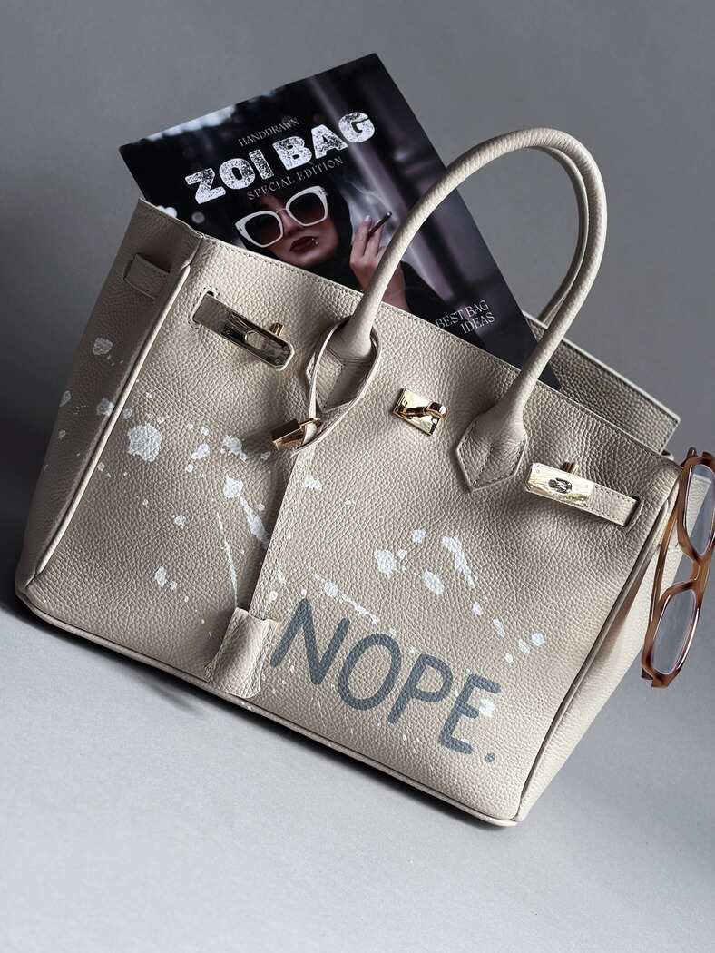 Béžová kožená kabelka Zoibag s ručně malovaným nápisem “Nope” a cákanci barvou. 