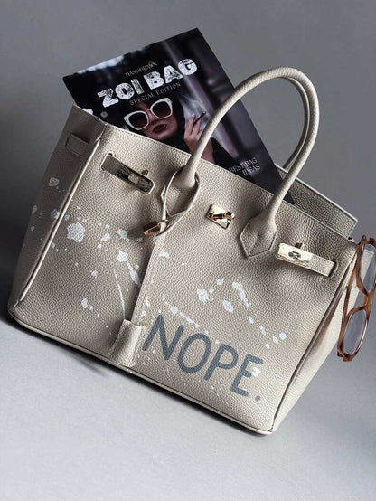 Béžová kožená kabelka Zoibag s ručně malovaným nápisem “Nope” a cákanci barvou. 