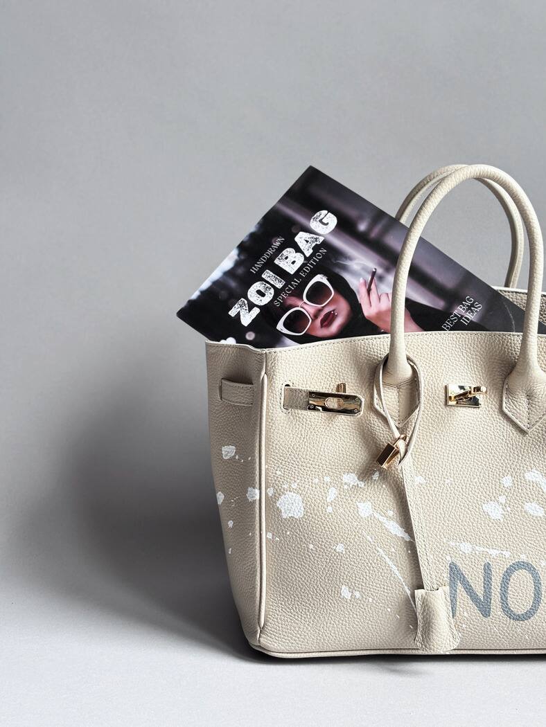 Béžová kožená kabelka Zoibag s ručně malovaným nápisem “Nope” a cákanci barvou. Detail kabelky.