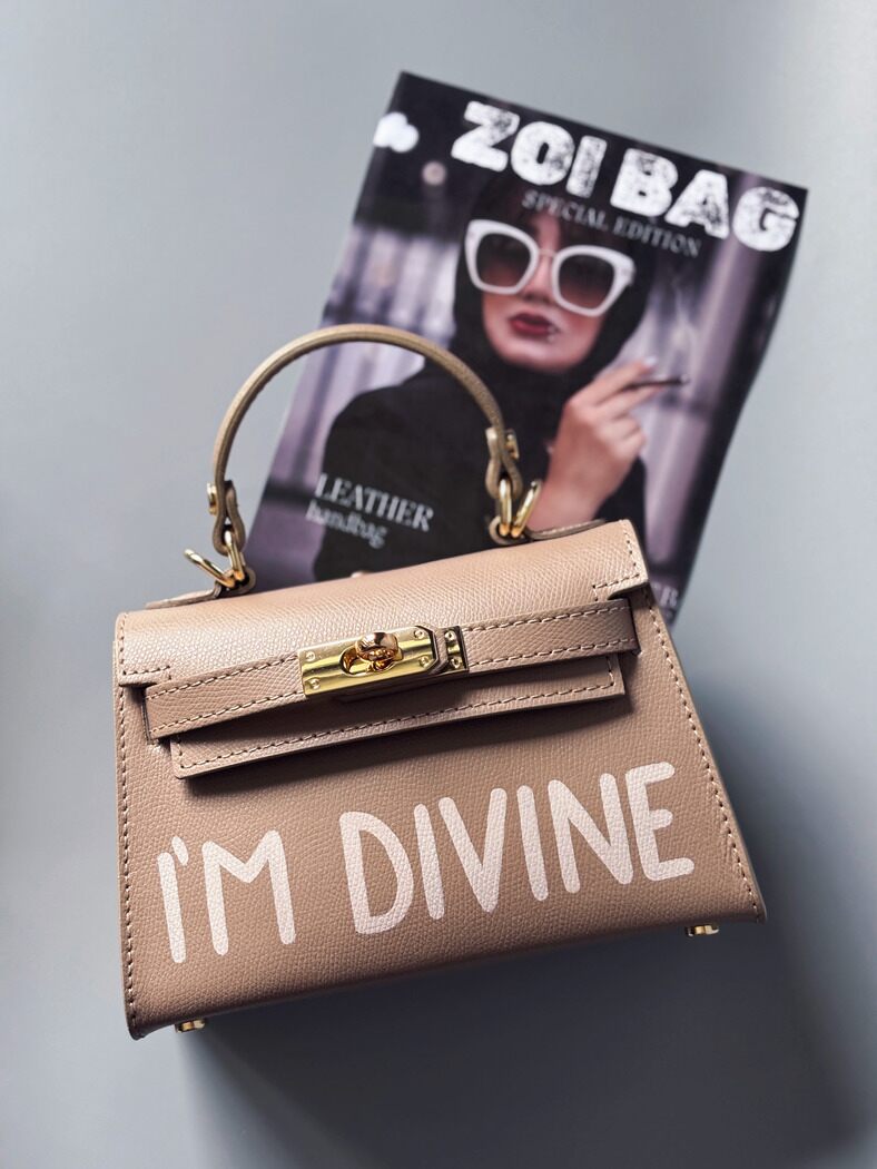 Designová luxusní béžová kabelka s ručně psaným nápisem, elegantním otočným zámkem a odnímatelným crossbody popruhem.