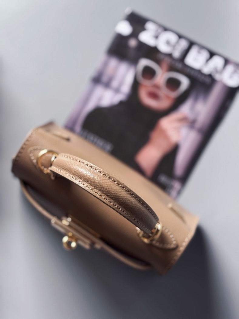 Designová luxusní béžová kabelka s ručně psaným nápisem, elegantním otočným zámkem a odnímatelným crossbody popruhem.