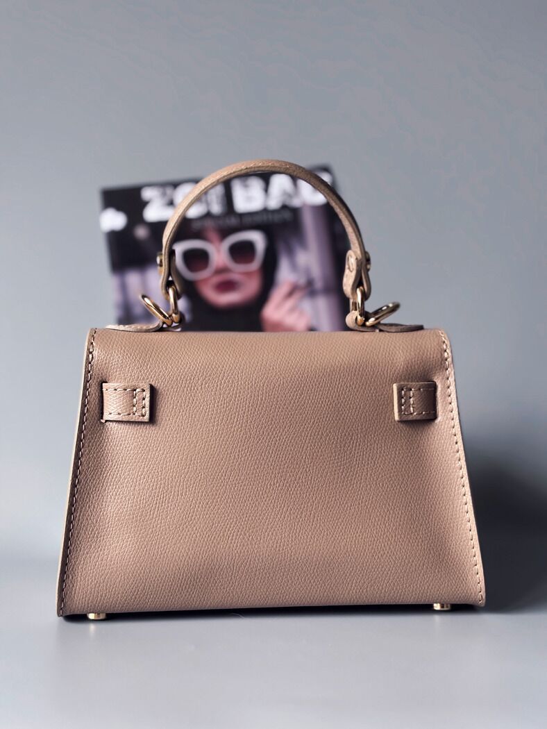 Designová luxusní béžová kabelka s ručně psaným nápisem, elegantním otočným zámkem a odnímatelným crossbody popruhem. Zezadu.