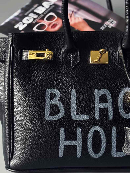 Černá velká kožená kabelka s ručně psaným nápisem "Black Hole" detail nápisu