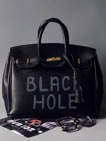 Černá velká kožená kabelka s ručně psaným nápisem "Black Hole" zapnutá