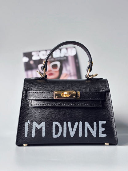 Designová luxusní černá kabelka s ručně psaným nápisem, elegantním otočným zámkem a odnímatelným crossbody popruhem.