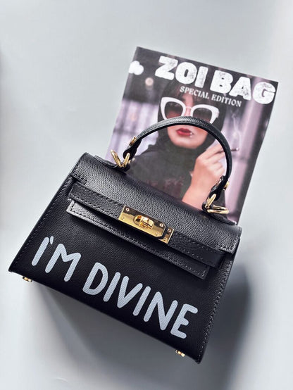 Designová luxusní černá kabelka s ručně psaným nápisem, elegantním otočným zámkem a odnímatelným crossbody popruhem.