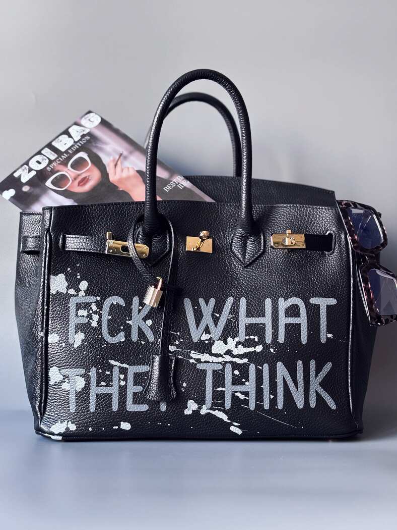 Luxusní designová kabelka Zoi Bag s ručně psaným nápisem a s cákanci barvou. Ikonické zapínání se zámkem a klíčkem.