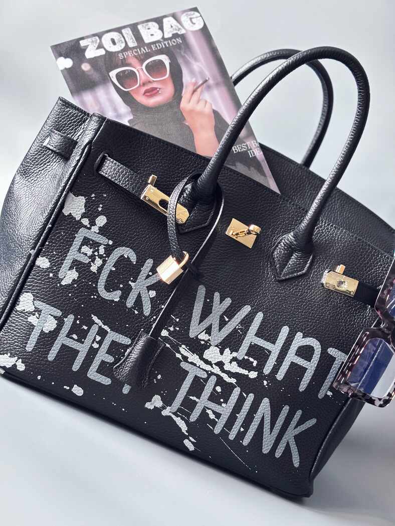Luxusní designová kabelka Zoi Bag s ručně psaným nápisem a s cákanci barvou. Ikonické zapínání se zámkem a klíčkem.