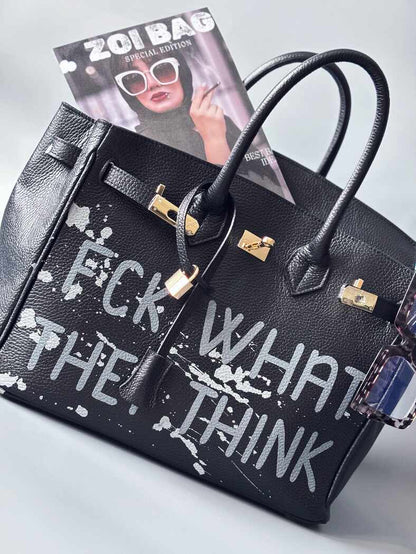 Luxusní designová kabelka Zoi Bag s ručně psaným nápisem a s cákanci barvou. Ikonické zapínání se zámkem a klíčkem.