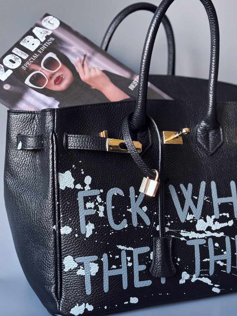 Luxusní designová kabelka Zoi Bag s ručně psaným nápisem a s cákanci barvou. Ikonické zapínání se zámkem a klíčkem. Detail nápisu.