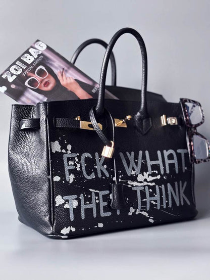 Luxusní designová kabelka Zoi Bag s ručně psaným nápisem a s cákanci barvou. Ikonické zapínání se zámkem a klíčkem.