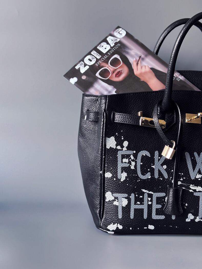 Luxusní designová kabelka Zoi Bag s ručně psaným nápisem a s cákanci barvou. Ikonické zapínání se zámkem a klíčkem. Detail nápisu.