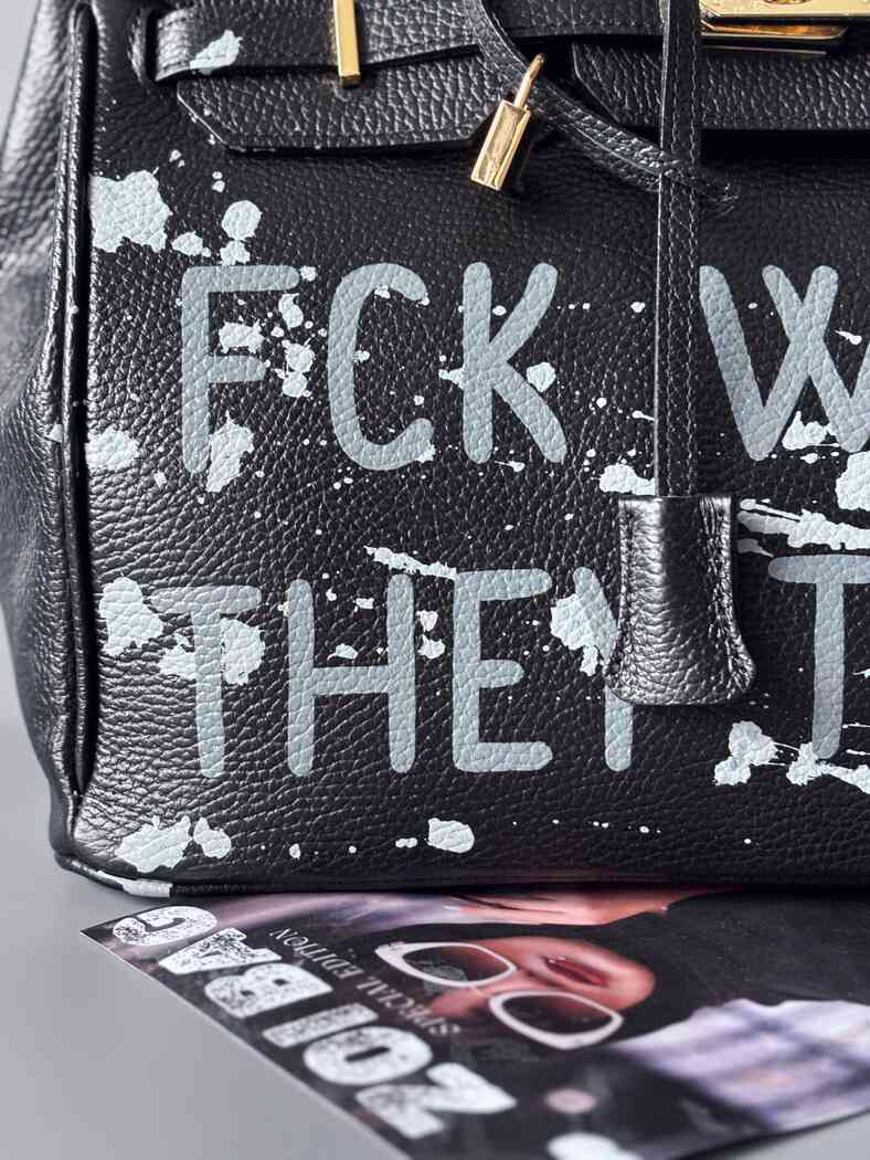 Luxusní designová kabelka Zoi Bag s ručně psaným nápisem a s cákanci barvou. Ikonické zapínání se zámkem a klíčkem. Detail nápisu.