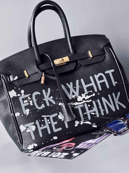 Luxusní designová kabelka Zoi Bag s ručně psaným nápisem a s cákanci barvou. Ikonické zapínání se zámkem a klíčkem. Zapnutá.