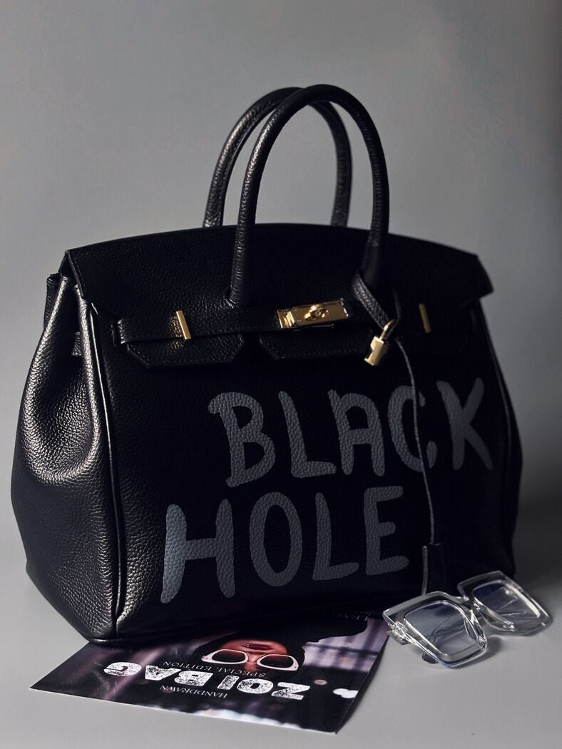 Černá velká kožená kabelka Zoi Bag s ručně psaným nápisem "Black Hole" z boku zapnutá