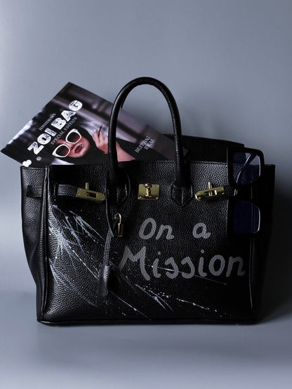 Černá kožená kabelka Zoi Bag s ručně psaným nápisem "On a Mision"