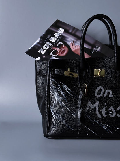 Extravagantní černá kožená kabelka Zoi Bag s ručně psaným nápisem "On a Mision"