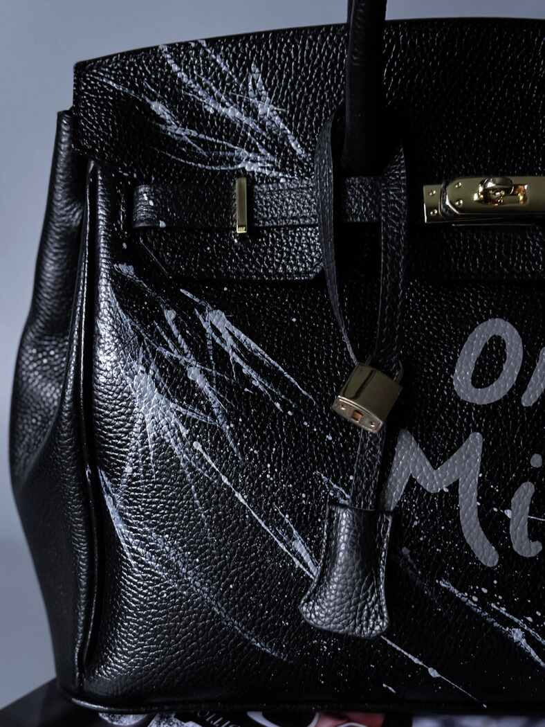 Černá kožená kabelka Zoi Bag s ručně psaným nápisem "On a Mision" detail cákanců