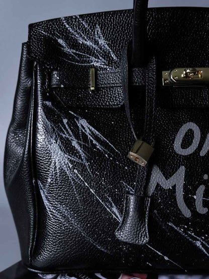 Černá kožená kabelka Zoi Bag s ručně psaným nápisem "On a Mision" detail cákanců