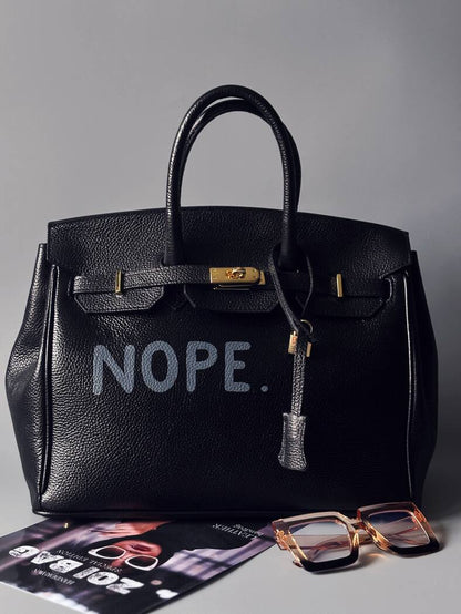 Černá velká kožená kabelka Zoi Bag s ručně psaným nápisem "Nope" zapnutá