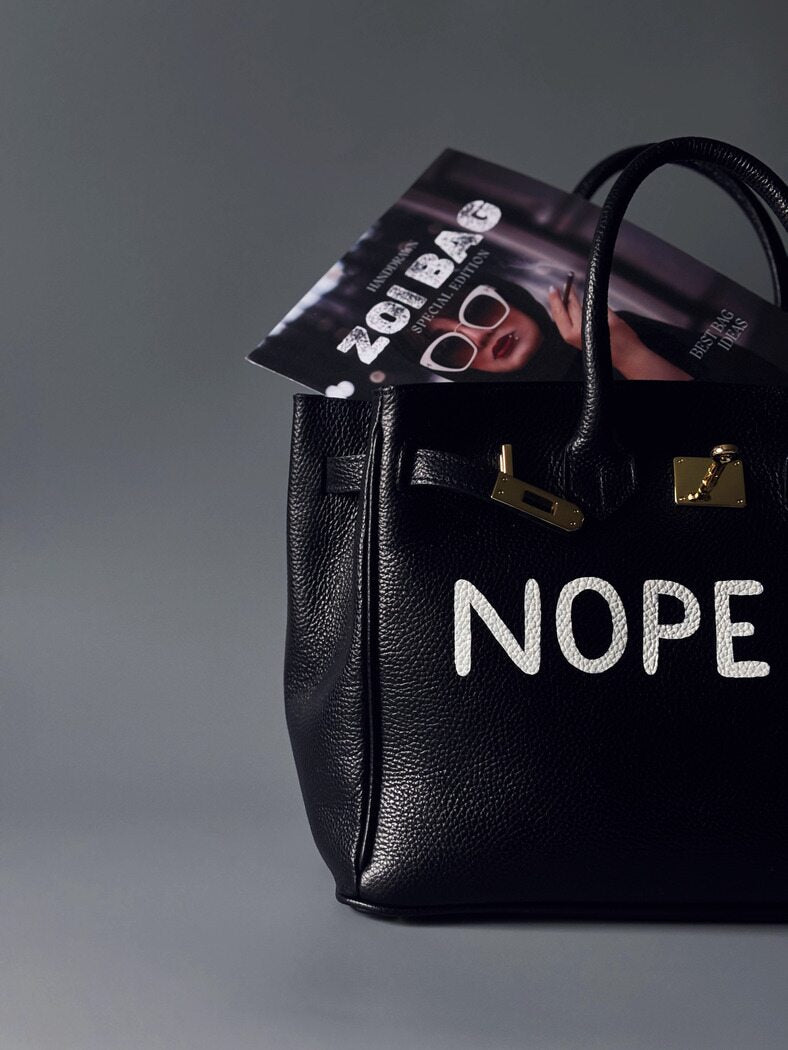 Černá kožená kabelka Zoi Bag s ručně psaným nápisem z pravé italské kůže se zapínáním pomocí ikonického zámku s klíčkem. Detail nápisu.