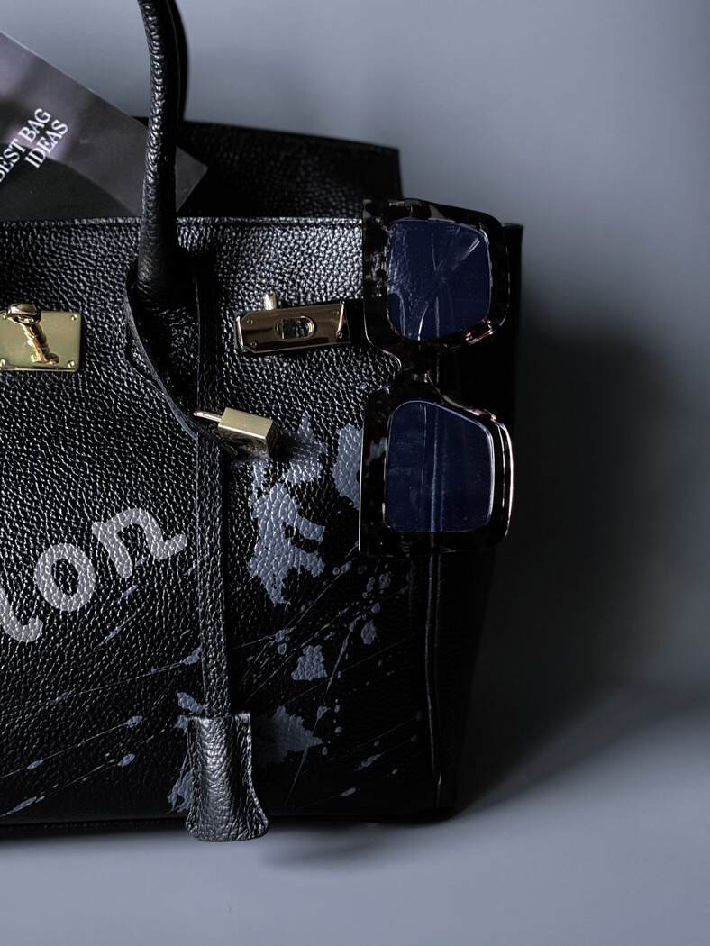 Velká černá kožená kabelka Zoi Bag s ručně psaným nápisem "On a Mission" detail cákanců