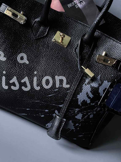 Velká černá kožená kabelka Zoi Bag s ručně psaným nápisem "On a Mission" detail cákanců