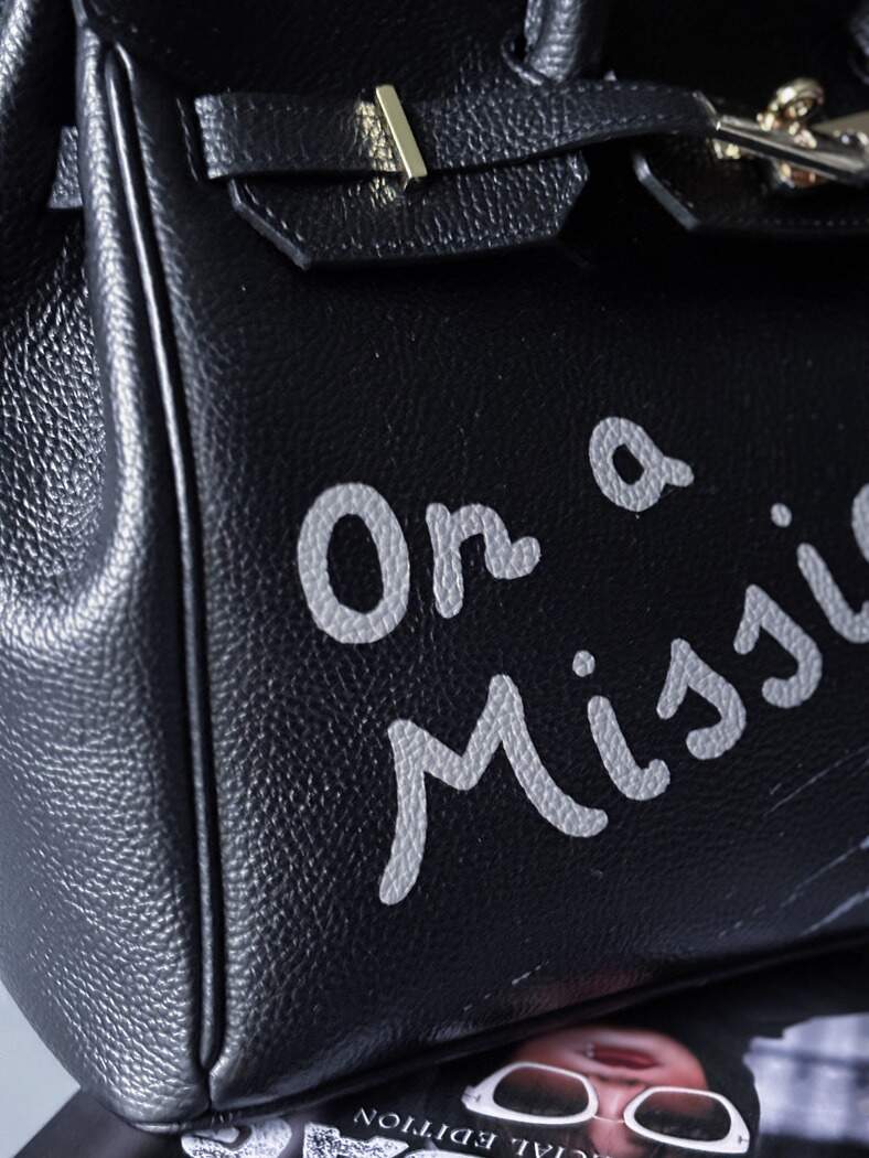 Velká černá kožená kabelka Zoi Bag s ručně psaným nápisem "On a Mission" detail nápisu