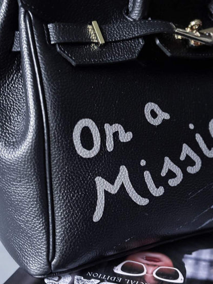 Velká černá kožená kabelka Zoi Bag s ručně psaným nápisem "On a Mission" detail nápisu