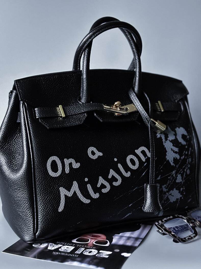 Velká černá kožená kabelka Zoi Bag s ručně psaným nápisem "On a Mission" zapnutá