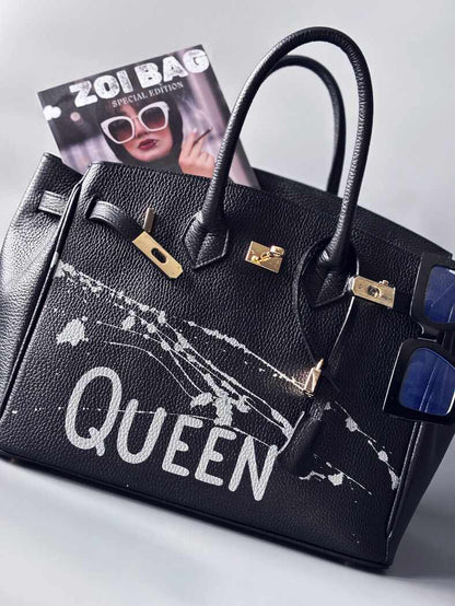 Designová luxusní kožená kabelka Zoi Bag s ručně psaným nápisem "Queen"a s cákanci barvou. Zapínání pomocí zámku a klíčku.