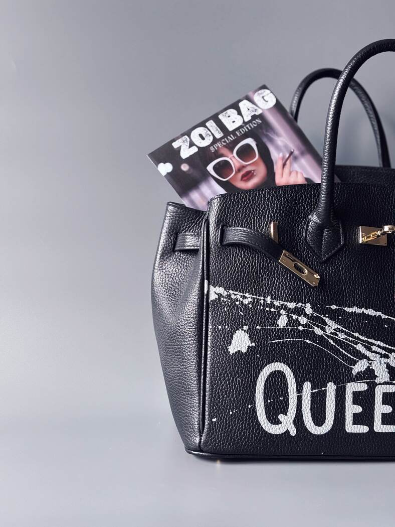 Designová luxusní kožená kabelka Zoi Bag s ručně psaným nápisem "Queen"a s cákanci barvou. Zapínání pomocí zámku a klíčku. Detail nápisu.
