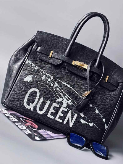 Designová luxusní kožená kabelka Zoi Bag s ručně psaným nápisem "Queen"a s cákanci barvou. Zapínání pomocí zámku a klíčku. Zapnutá.