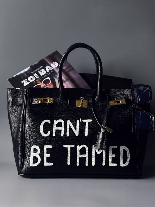 Luxusní černá dámská kabelka Zoi Bag z pravé italské kůže s ručně psaným nápisem "Can't be tamed"