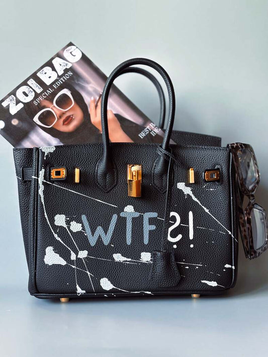 Designová černá kožená kabelka Zoi Bag z právé kůže s ručně psaným nápisem a cákanci barvou. Zlatý zámek s klíčkem.