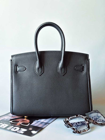 Zezadu. Designová černá kožená kabelka Zoi Bag z právé kůže s ručně psaným nápisem a cákanci barvou. Zlatý zámek s klíčkem.