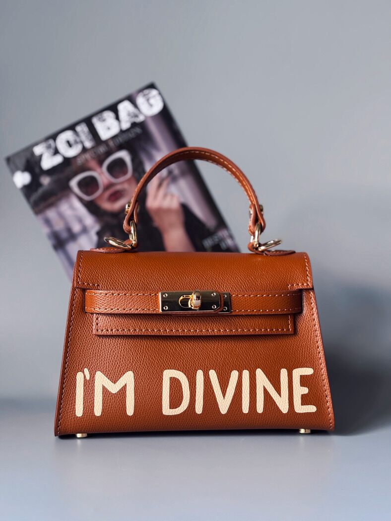 Designová luxusní hnědá kabelka s ručně psaným nápisem, elegantním otočným zámkem a odnímatelným crossbody popruhem.