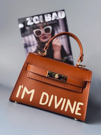 Designová luxusní hnědá kabelka s ručně psaným nápisem, elegantním otočným zámkem a odnímatelným crossbody popruhem.