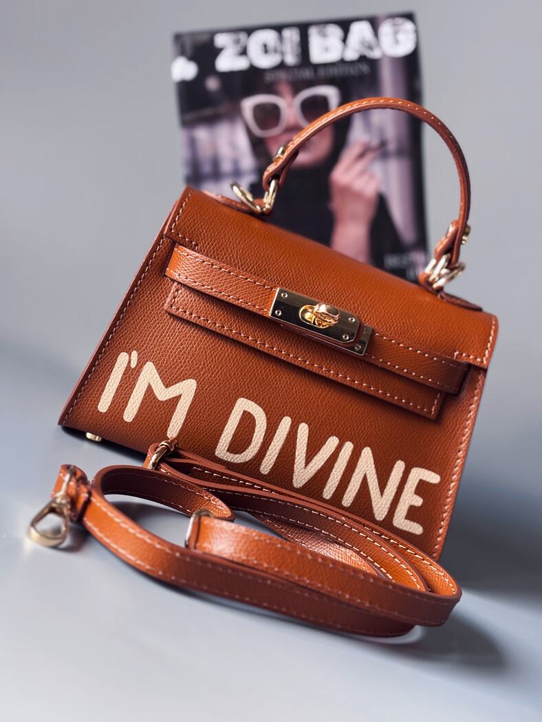 Designová luxusní hnědá kabelka s ručně psaným nápisem, elegantním otočným zámkem a odnímatelným crossbody popruhem. 