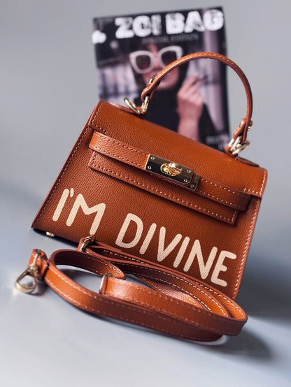 Designová luxusní hnědá kabelka s ručně psaným nápisem, elegantním otočným zámkem a odnímatelným crossbody popruhem. 